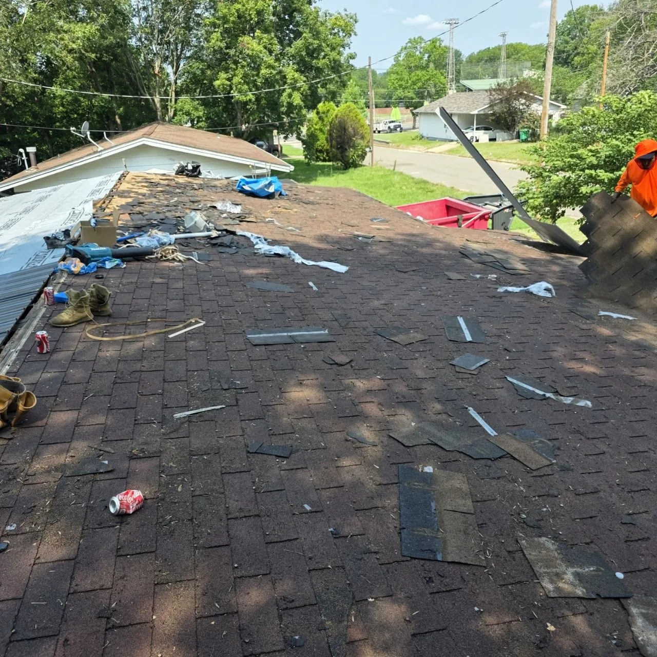 Roofing crew removing aged asphalt shingles during a residential roof tear-off