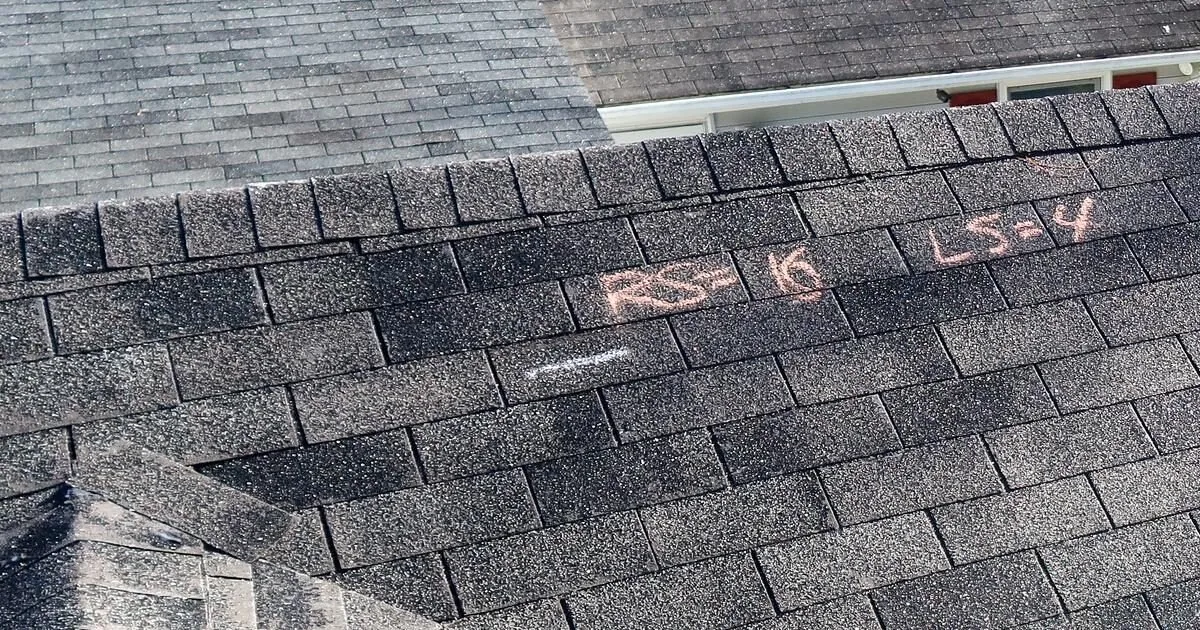 Gray roof shingles with light chalk markings across the shingle surface